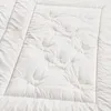 A close-up, overhead view of a white quilted comforter. Produktbild-Vorschau
