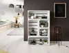 A room with a white wooden floor, white brick wall, and a dark gray wall. A white shelving unit made of wooden crates is filled with books and decorative items. A bed with light wood drawers is visible on the left. A floor lamp with a dark glass shade stan Produktbild-Vorschau