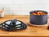 A glass lid for a pot is shown on the left, and a pot filled with food is on the right, both on a wooden countertop. Voir les images du produit