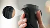 A hand is holding a black kitchen mixer with a magnified inset showing a detail of the handle. Produktbild-Vorschau