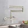 A kitchen faucet mounted on a wall above a sink, with a bowl of fruit on the counter. Podgląd zdjęcia produktu