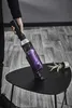 A person is holding a cordless vacuum cleaner over a black table with spilled dirt and a small potted plant. Voir les images du produit