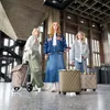 Three women standing in a large, industrial-style building with concrete walls and ceilings, each with a shopping trolley. Voir les images du produit