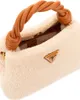 A close-up view of a fluffy beige handbag with a twisted brown handle and a gold Guess logo. Produktbild-Vorschau