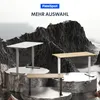 Three adjustable desks are displayed on rocky platforms against a dramatic mountain backdrop. Produktbild-Vorschau