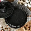 A black speckled bundt cake pan and a round cake pan are shown on a wooden surface with a patterned cloth and hazelnuts. Anteprima dell’immagine prodotto