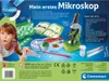 The image shows the packaging of a children's microscope kit, with a girl looking at the camera and various components of the kit laid out. Náhľad obrázku produktu