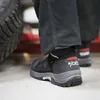 Close-up of a person's foot wearing a black safety boot with red accents and a grey sole. Produktbild-Vorschau