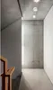 A modern interior hallway with concrete walls and ceiling, featuring a staircase railing and ceiling lights. Podgląd zdjęcia produktu