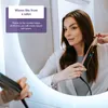 A woman is using a hair straightener to curl her hair in front of a mirror. Produktbild-Vorschau
