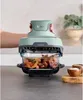 A hand is shown operating a green and gray Ninja CRISPi air fryer, which is cooking food in a glass dish. Anteprima dell’immagine prodotto