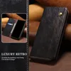 A black leather phone case with stitching and a snap closure, shown with a smaller inset image of a phone inside a similar case with cards. Produktbild-Vorschau
