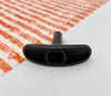 A black starter handle is placed on a white surface, with a white sheet of packaging material with orange text in the background. Produktbild-Vorschau
