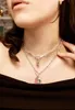 A close-up shot of a person wearing two layered necklaces. Anteprima dell’immagine prodotto