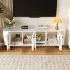A white TV stand with open doors, displaying various items inside, in a living room setting. Podgląd zdjęcia produktu