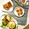 A spread of appetizers and tarts on a table with a grey linen cloth. Podgląd zdjęcia produktu