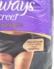 A close-up of a person's lower body wearing black underwear, with packaging visible in the background. Produktbild-Vorschau