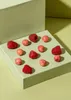 A light green box with several raspberries and pink candy balls arranged on top, set against a light yellow background. Produktbild-Vorschau