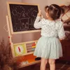 A young girl is drawing on a double-sided easel. Produktbild-Vorschau