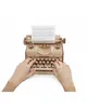 A wooden model typewriter with paper in the roller, and hands typing on the keyboard. Podgląd zdjęcia produktu