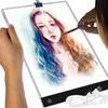 A person is using a light pad to trace a drawing of a woman's face. Náhled obrázku produktu