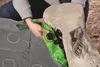 A person is shown folding an air mattress into a storage bag. Podgląd zdjęcia produktu