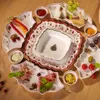 A collection of Christmas-themed ceramic dishes and serving platters arranged on a wooden table, filled with various food items like cheese, grapes, cured meats, olives, and condiments. Anteprima dell’immagine prodotto