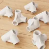 Several white plastic connectors are arranged on a wooden surface. Podgląd zdjęcia produktu