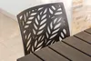 A close-up of a black chair with a leaf pattern on its back, next to a dark wooden table. Anteprima dell’immagine prodotto