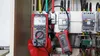 A person wearing a red glove is holding a UNI-T True RMS Solar-Multimeter UT196 and using it to test electrical components in a panel. Produktbild-Vorschau