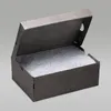 An open gray cardboard shoe box with speckled white tissue paper inside, set against a plain gray background. Produktbild-Vorschau
