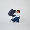 A young person is crouching with a large backpack on their back. Voir les images du produit