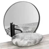 A marble basin and faucet are displayed on a wooden surface in front of a round mirror. Náhled obrázku produktu