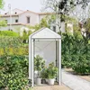 A small greenhouse in a garden setting, with plants inside and a house in the background. Produktbild-Vorschau