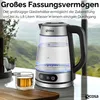 A glass electric kettle with blue LED lighting is shown on a countertop, with a small glass of tea next to it. The background features a scenic view of mountains and greenery. Náhľad obrázku produktu
