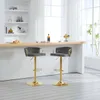 Two dark gray bar stools with gold legs are placed in front of a bar counter. Produktbild-Vorschau