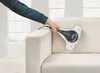 A hand is using a handheld vacuum cleaner on a white sofa. Produktbild-Vorschau