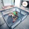 A woman and a baby are playing inside a large playpen in a living room. Produktbild-Vorschau