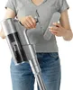 A person is holding a cordless vacuum cleaner and an accessory. Produktbild-Vorschau