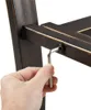A hand is using an Allen wrench to tighten a bolt on a metal bench frame. Produktbild-Vorschau