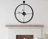 A black metal wall clock hangs above a white brick fireplace. Podgląd zdjęcia produktu