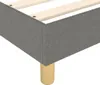 A close-up view of the corner of a dark gray fabric upholstered box spring bed frame with wooden legs. Náhled obrázku produktu