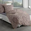 A bed with patterned bedding and pillows in a room with a large window overlooking a landscape. Produktbild-Vorschau
