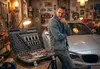 A man is standing in a garage next to a car, with a large toolbox open in the foreground. Produktbild-Vorschau