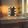 A lighted makeup mirror sits on a vanity desk. Náhľad obrázku produktu