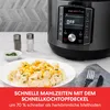 A multicooker is shown next to a plate of food, with salt and pepper shakers and a napkin with cutlery. Produktbild-Vorschau