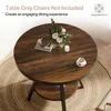 A round wooden dining table with a metal base, decorated with a vase of flowers, a book, a candle, and a cup of coffee. Produktbild-Vorschau