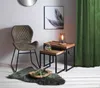 A chair and side tables are arranged in a room with a green curtain and a framed picture on the wall. Produktbild-Vorschau