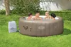 Four people relaxing in an inflatable hot tub in a grassy backyard. Produktbild-Vorschau