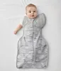 A baby lying on its back on a white surface, wearing a sleep sack. Produktbild-Vorschau